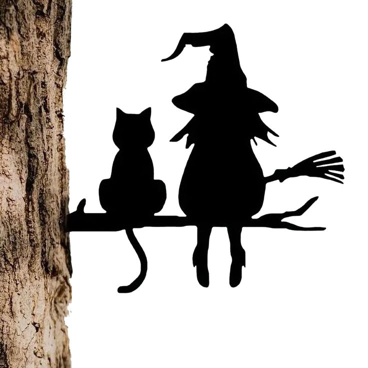 two cats sitting on top of a tree branch next to a witch's hat