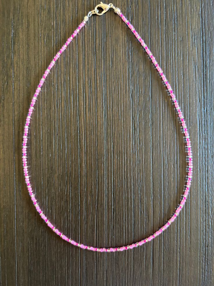 a pink beaded necklace on a wooden surface