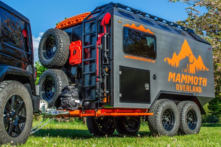 a black truck with orange lettering on the side and two large tires attached to it