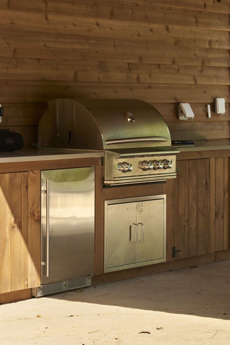 an outdoor kitchen with stainless steel appliances and wood paneling