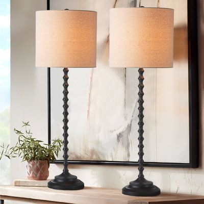 two lamps sitting on top of a wooden table next to a mirror and potted plant