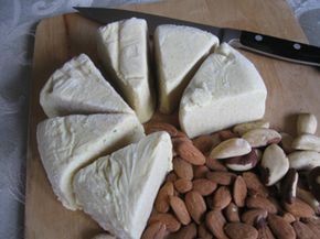 a cutting board topped with cheese and nuts next to a knife