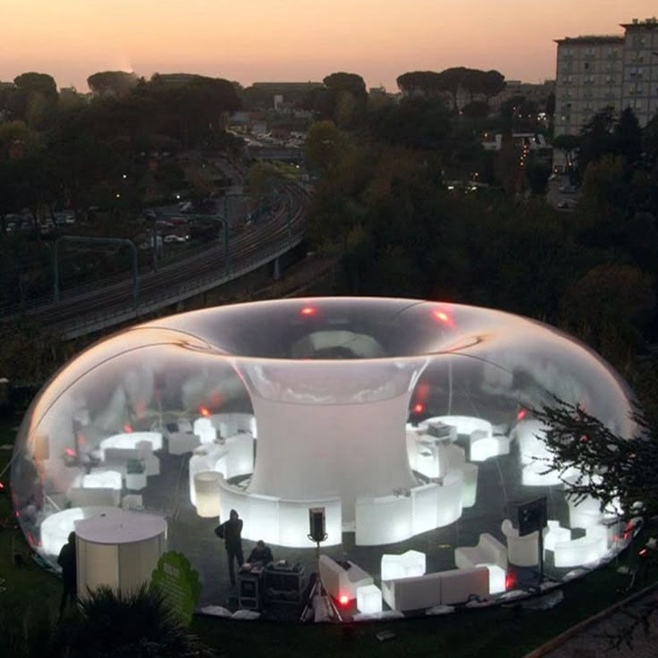 an aerial view of a large white tent with lights on it's sides and surrounding seating areas