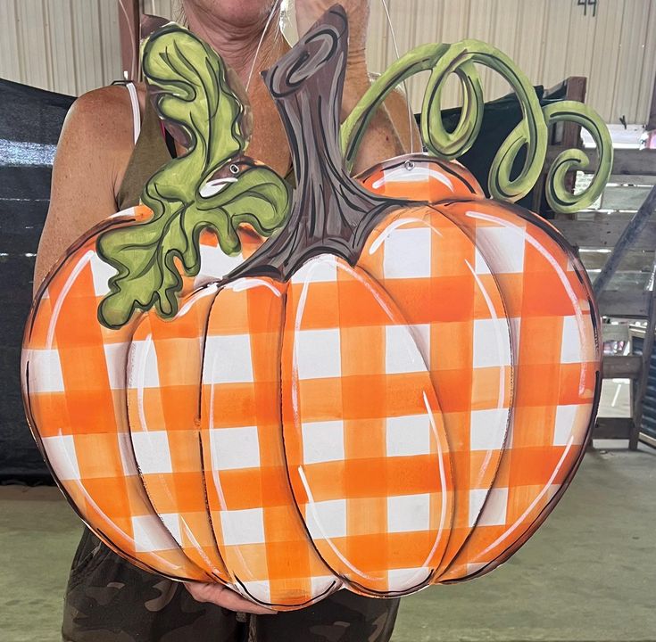 a woman holding up a pumpkin shaped paper cutout