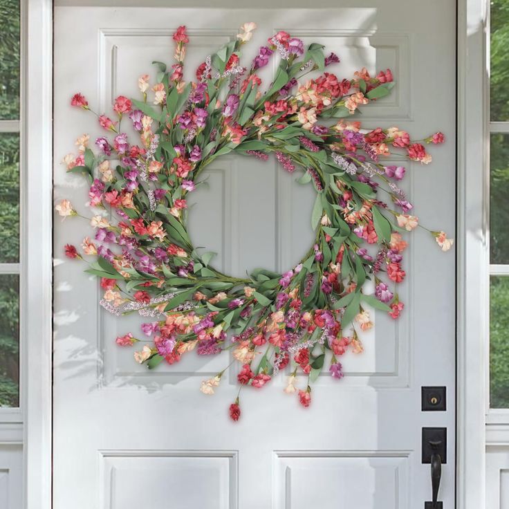 a wreath is hanging on the front door with pink and purple flowers in it,