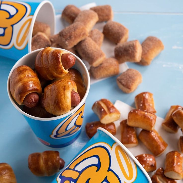 two cups filled with doughnuts sitting on top of a blue table next to donuts