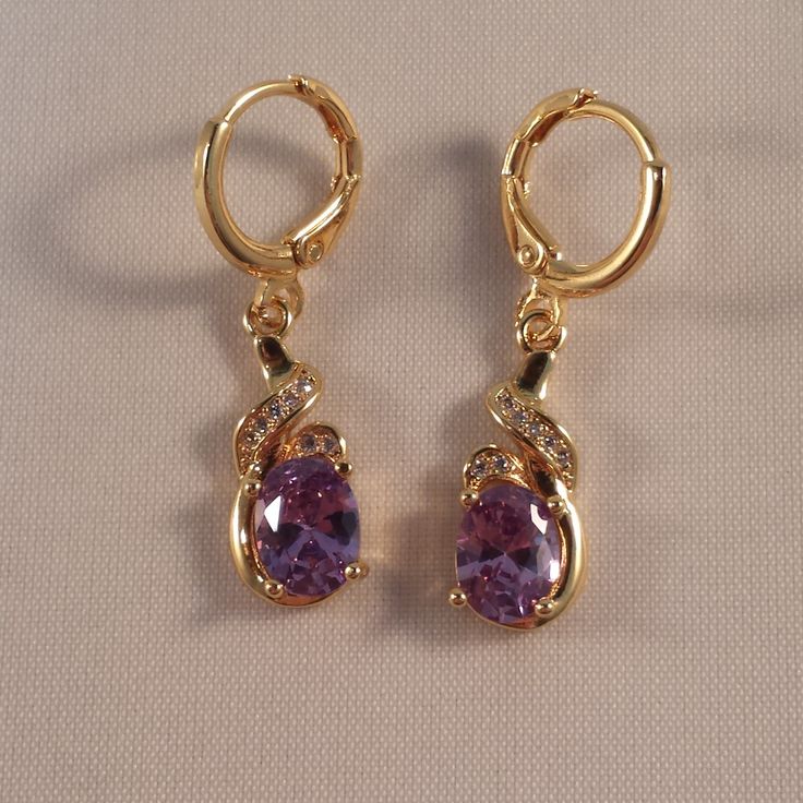 These Beautiful Purple Topaz Ribbon Swirl Earrings Are Made Of 18k Yellow Gold Filled. The Large Oval Topaz Zircon (Lab Created) Stones Are 6x8mm And With A Swirl Of Smaller White Topaz Stones. Brand New And Never Been Worn. Lead And Nickel Free. These Fine Quality Earrings Are Perfect And Comfortable For Special Occasions Or A Special Gift. Please Send Offers And Questions. Big Stone :6 X 8mm Or .24" X .31" Earrings: 1.22" X .31" Fastening: Hoop Clasp (Pierced) Hoop Diameter: .47" Elegant Gold Amethyst Crystal Earrings, Amethyst Earrings Gold, Purple Amethyst Earrings, Purple Gems, Swirl Earrings, Amethyst Jewelry, Topaz Stone, Amethyst Earrings, White Topaz