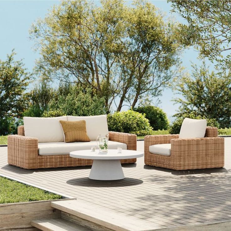 an outdoor living room with wicker furniture and white cushions on the outside decking