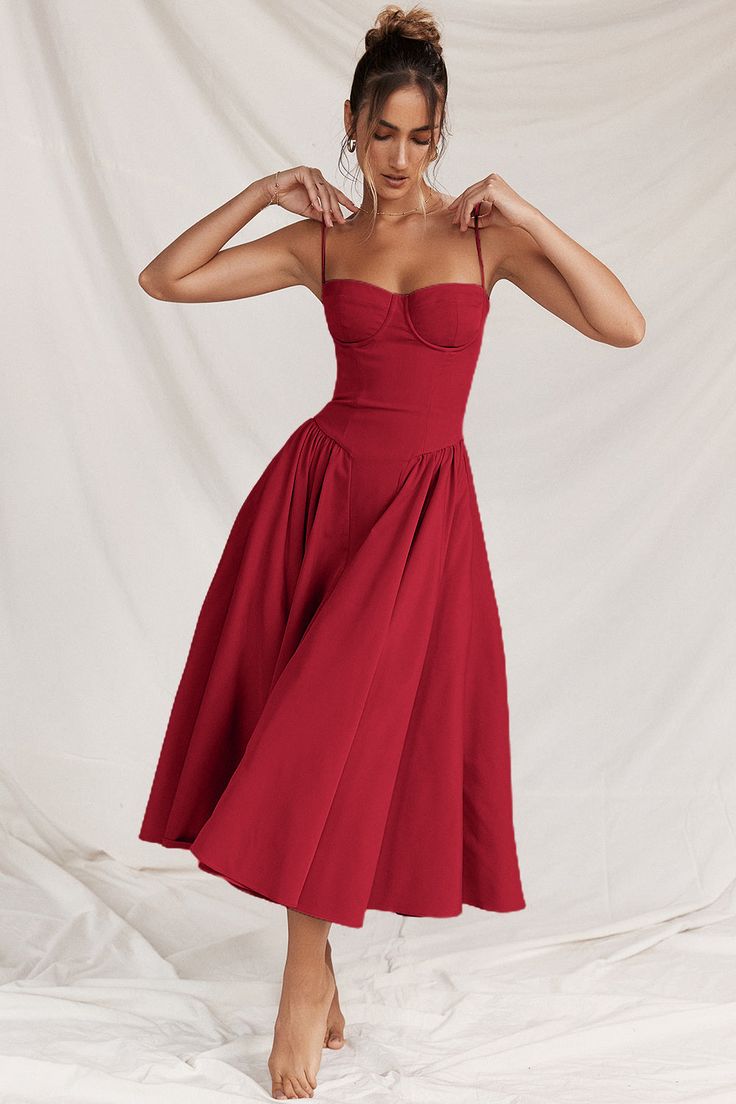 a woman in a red dress posing for the camera with her hands on her hips