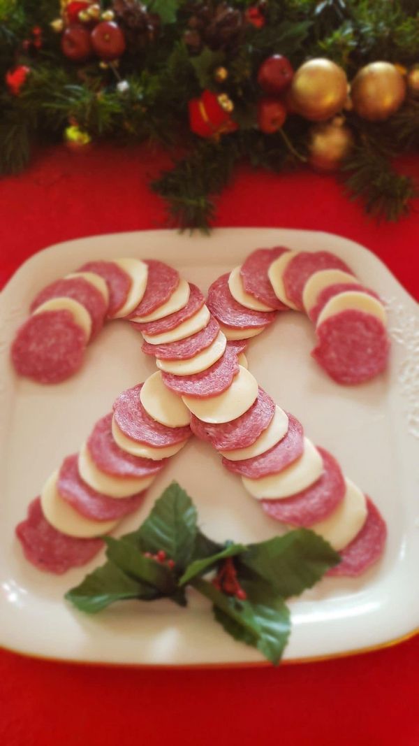 a white plate topped with slices of meat and veggies next to a christmas tree