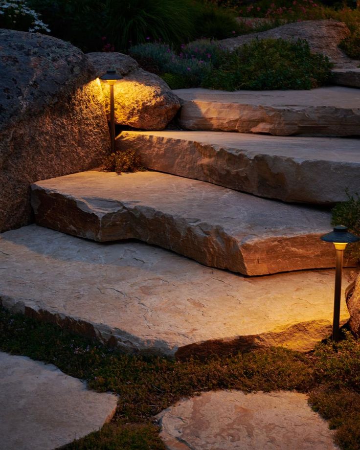 some steps lit up with lights in the grass and rocks on either side of them