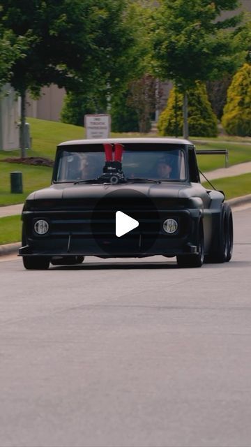 an old black truck driving down the street