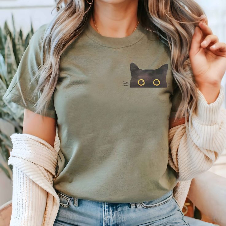 a woman wearing a green t - shirt with a black cat embroidered on the front