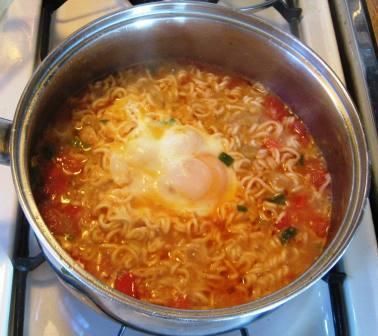 a pot filled with noodles and an egg on top of the burner next to a stove