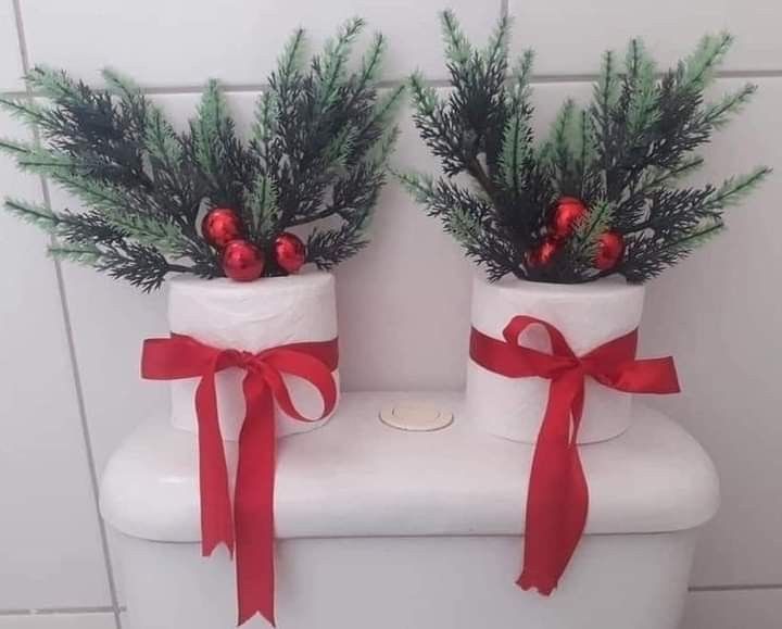 two christmas decorations are sitting on top of a toilet