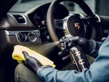 a man cleaning the inside of a car with a yellow microfibrel cloth