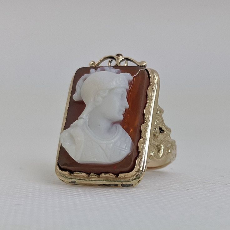 This gorgeous vintage cameo ring is beautifully crafted in a solid 14k gold frame with details at every angle. The victorian style is likely a 1930-1950s creation. In the center is a carved shell cameo of a Roman soldier. The cameo is in excellent condition and the sturdy ring measures approximately 26.45mm tall (including gold filigree fame) x 17.37mm wide. The ring is currently a ring size 7.5 but can be resized by your trusted local jeweler. A bold statement ring for men and women who love an Vintage 14k Gold Cameo Rings, Vintage Yellow Gold Cameo Rings, Antique Cameo Ring Jewelry, Art Deco Cameo Ring For Collectors, Antique Oval Cameo Signet Ring, Cameo 14k Gold Rings For Collectors, Antique Cameo Signet Ring For Weddings, Collectible 14k Gold Cameo Rings, Art Deco Cameo Ring Collectible