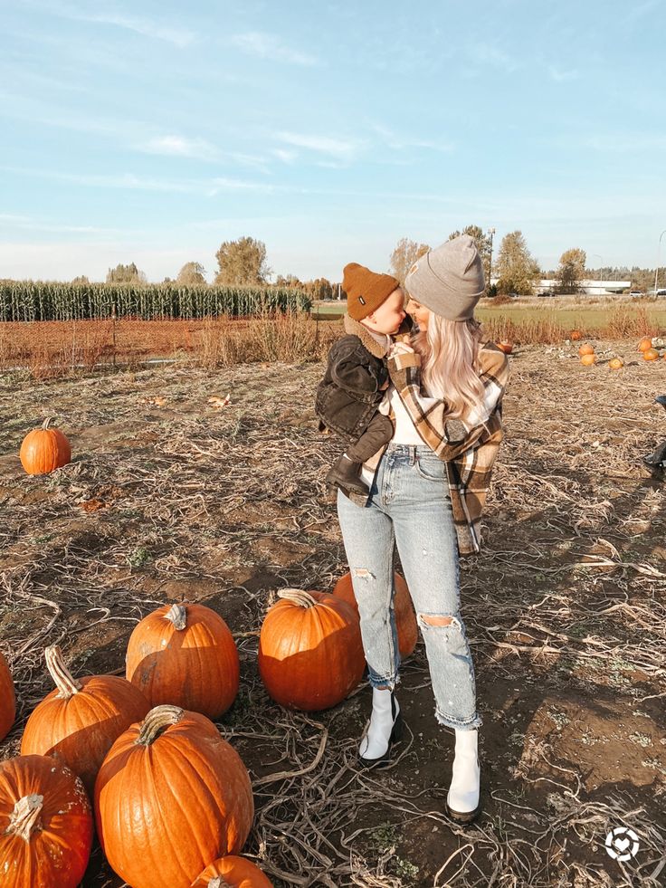 a woman standing in a field surrounded by pumpkins