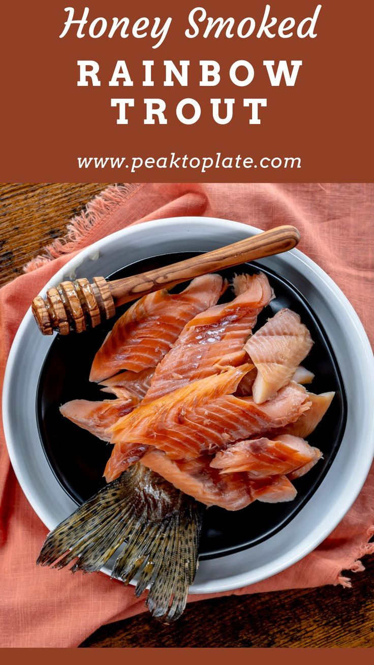 honey smoked rainbow trout on a black plate next to a pink napkin and wooden utensils