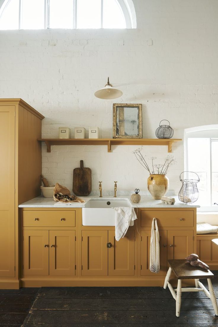 a kitchen with wooden cabinets and white walls, an open window above the sink area