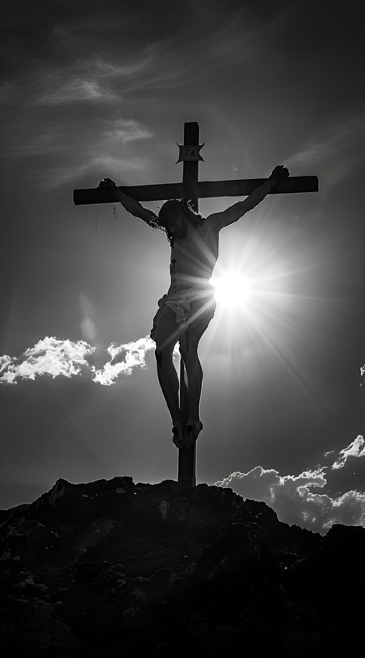 black and white photograph of jesus on the cross with sun shining through clouds in background