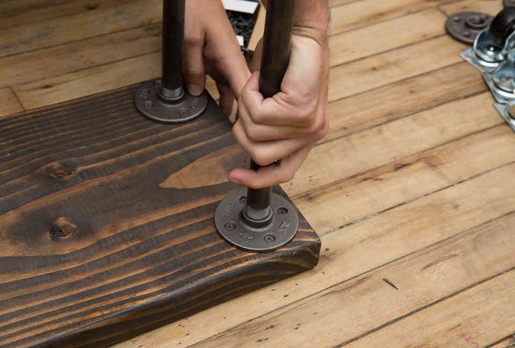 a person is working on a wooden table with metal feet and nails in the center