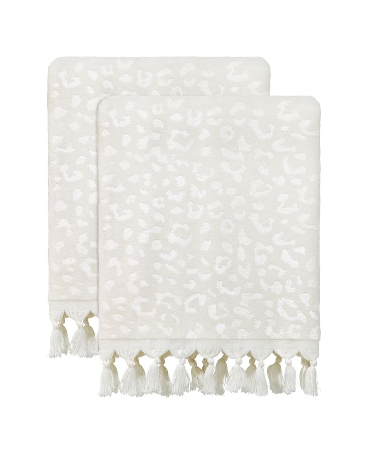 two white towels with tassels on the bottom and one in leopard print, both folded