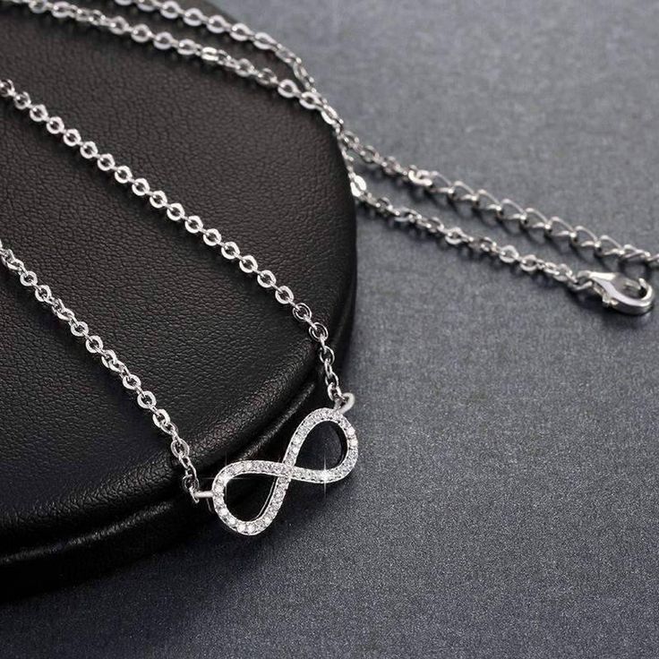 Centered between the two lengths of shiny silver tone chain, this miniature eternity symbol appears to float along the neck. Completely encrusted in micro CZ stones creating incredible shimmer. At only 2 cm this is truly subtle and graceful. This necklace is perfect for women, teens or young children. Length: 18 inch chain Stones: CZ Metal: Sterling Silver, 3 layers of platinum plating. Comes in a gift box. (Reg $45.99) Silver Infinity Clavicle Chain Jewelry, Silver Infinity Jewelry, Silver Infinity Necklace In Dainty Style, Silver Infinity Dainty Necklace, Silver Dainty Infinity Necklace, Dainty Silver Infinity Necklace, Silver Infinity Chain Jewelry, Silver Infinity Clavicle Chain Necklace, Silver Cubic Zirconia Necklace With Cable Chain