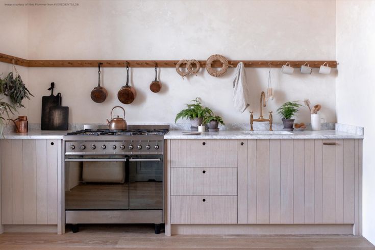 a kitchen with pots and pans hanging on the wall next to an open oven