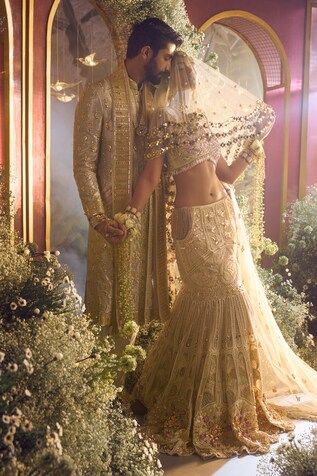 a man and woman standing next to each other in front of flowers on the ground