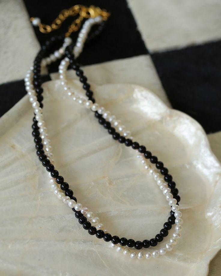 Experience the timeless contrast between black onyx and white pearls with this simple yet striking design. Natural pearls add a soft beauty, while black agate adds a unique charm. This necklace can be DIY by yourself. The two beads are scattered and have a sense of hierarchy. They are twisted together and have a sense of design.But you can't take it apart and wear it alone~ Classic Black Pearl Chain Necklace, Black Pearl Necklaces With Pearl Charm, Black Pearl Jewelry With Pearl Charm, Black Pearl Necklace With Pearl Charm, Black Beaded Necklaces With Pearl Charm Gift, Black Pearl Necklace With Round Beads And Pearl Drop, Black Beaded Necklace With Pearl Charm As Gift, Black Pearl Drop Necklace, Black Pearl Drop Necklace With Round Beads