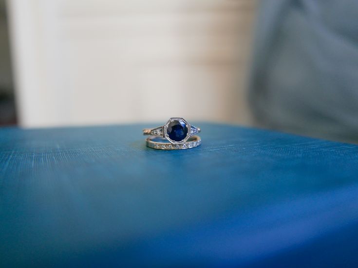 a close up of a ring on a blue table with a chair in the background