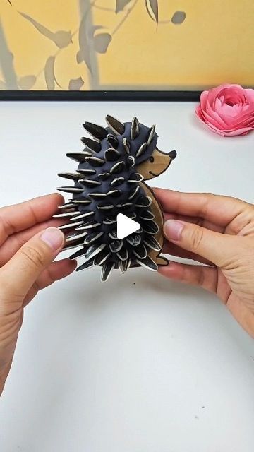 someone is holding a fake hedgehog toy in their hands and it's made out of paper