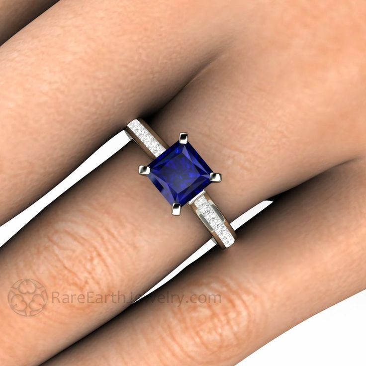 "A stunning contemporary Blue Sapphire engagement ring in a Gold or Platinum solitaire setting. This Blue Sapphire ring has a 1.5 carat princess cut Blue Sapphire accented with a .50cts of channel set princess cut diamonds in a cathedral style setting with a sleek and stylish square band and prongs. Blue Sapphire is the birthstone for September. Available in 14K or 18K White, Yellow or Rose Gold or Platinum. Made to order. Please allow three to four weeks for delivery. Inquire for the matching w Princess Cut Jewelry With Accent Stones, Modern Blue Radiant Cut Rings, Modern Blue Asscher Cut Rings, Blue Diamond Ring With Square Cut, Square Cut Sapphire Ring For Anniversary, Fine Jewelry Sapphire Diamond Ring With Square Cut, Fine Jewelry Sapphire Square Cut Diamond Ring, Sapphire Square Cut Ring With Accent Stones, Square Cut Sapphire Ring Fine Jewelry