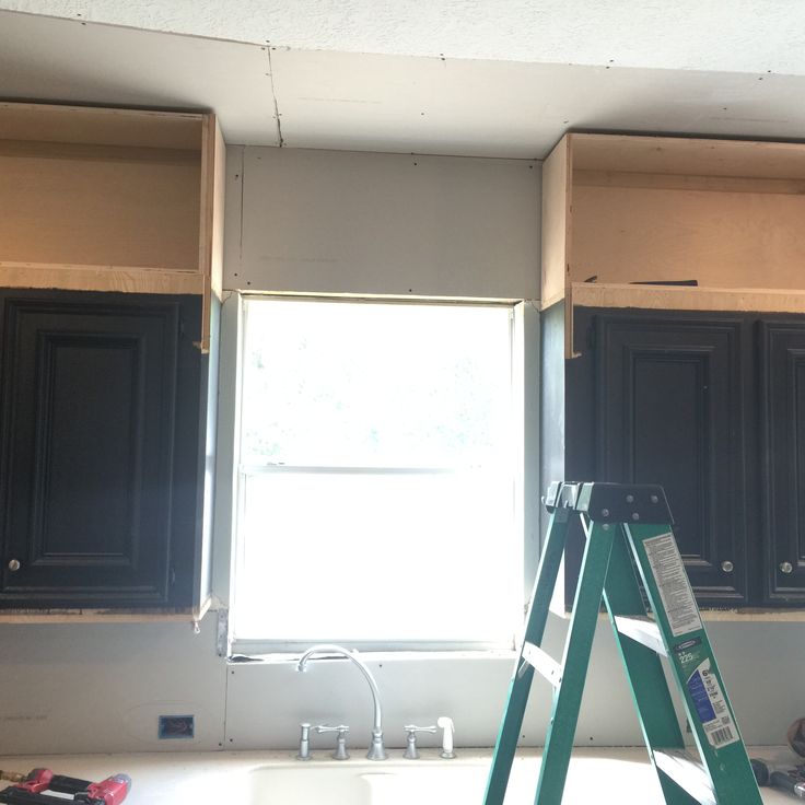 a ladder in front of a window with black cabinets