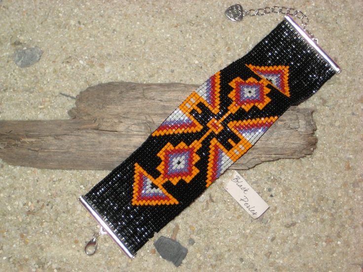 a beaded bracelet on a piece of driftwood with a tag attached to it