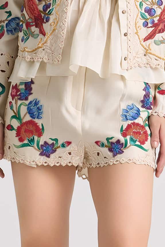 Ivory shorts featuring multi-color floral applique and beadwork. - Aza Fashions Summer Cream Bottoms With Floral Embroidery, Cream Floral Embroidery Bottoms For Summer, Summer Floral Embroidery Cream Bottoms, Summer Embroidered Beige Pants, Beige Floral Embroidered Bottoms For Spring, Beige Floral Embroidery Pants For Summer, Spring Beige Floral Embroidered Bottoms, Bohemian Multicolor Bottoms With Floral Embroidery, White Floral Embroidered Bottoms For Summer