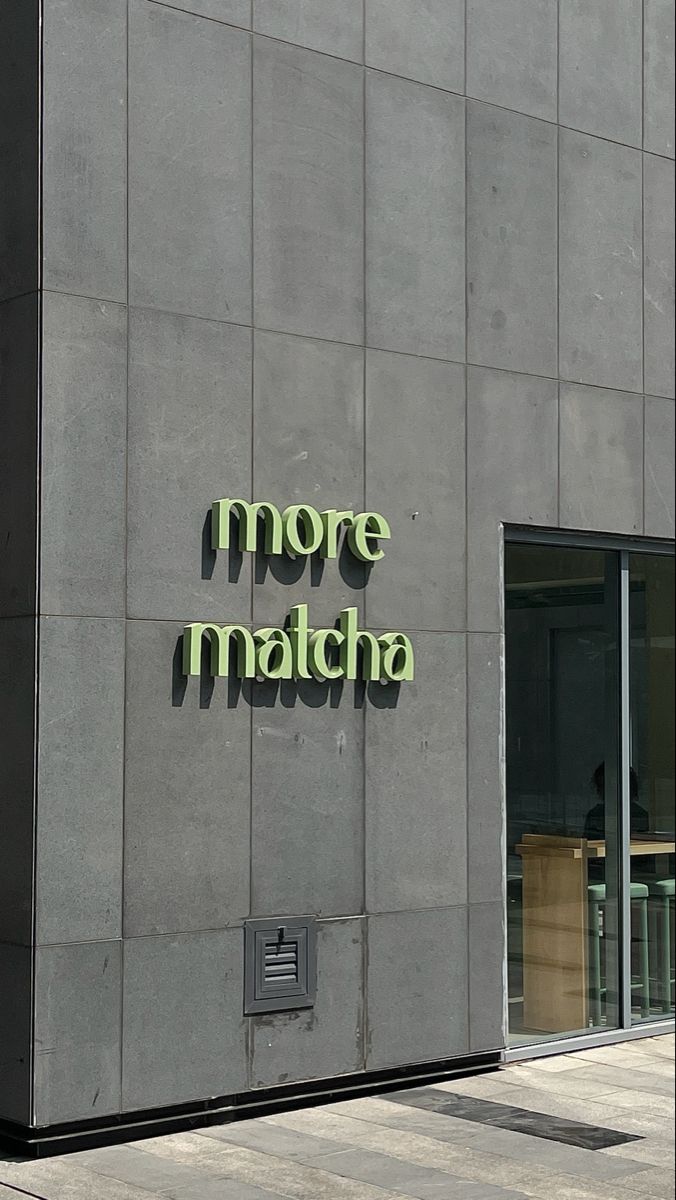 there is a sign that says more matcha on the side of a gray building