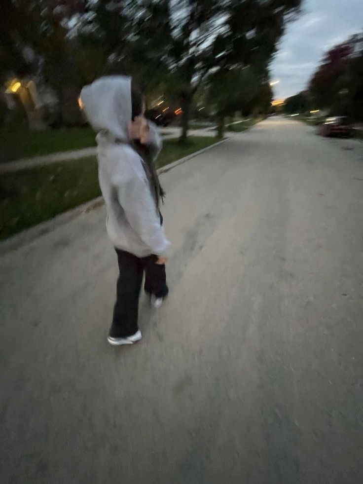 a person in a hoodie is skateboarding down the street