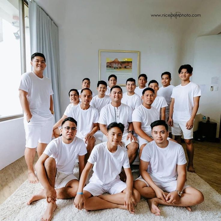 a group of young men sitting on top of a bed in front of a window