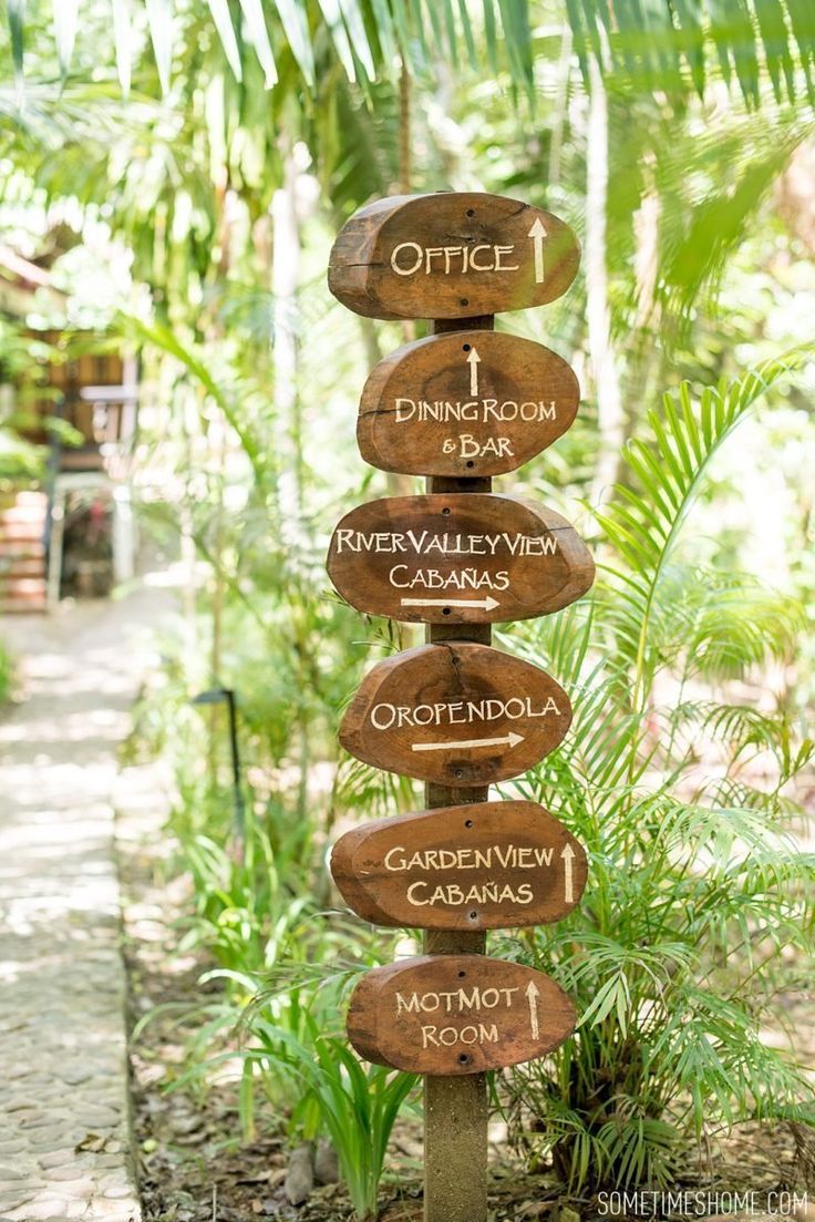 a wooden sign in the middle of a forest with directions to different places on it