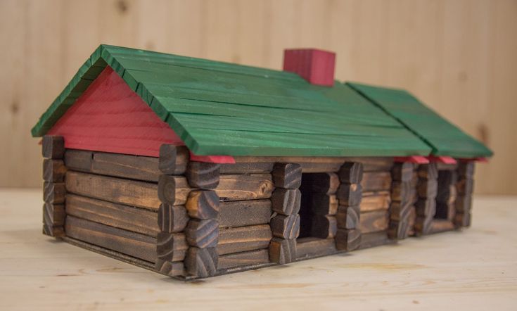 a toy house made out of wood with green roof and red shingles on top