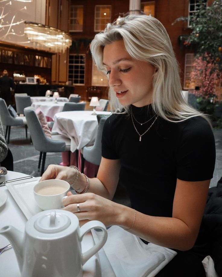 a woman sitting at a table with a cup of coffee