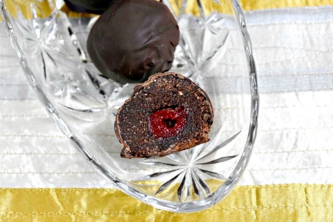 three chocolate candies in a glass dish on a yellow and white striped tablecloth