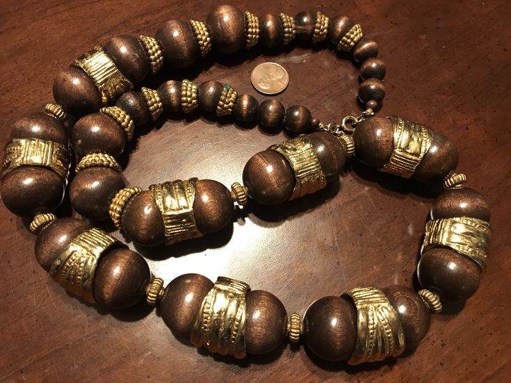 "Vintage Cadoro Wooden Bead and Gold Ring Necklace The necklace is signed \"CADORO\" and measures 30\". The necklace has been well-maintained and cared for over the years. It is in good vintage condition. -------------------------- CADORO - JEWELLERY TO THE RICH AND FAMOUS, Cadoro is very high quality jewellery and was founded by Actor Steve Brody and Dan Staneskieu in 1945. They traveled all over the world to source only the highest quality materials. It was originally very expensive, fashion f Vintage Gold Jewelry With Wooden Beads, Festival Jewelry With Gold Wooden Beads, Gold Jewelry With Wooden Beads For Festivals, Brown Large Beads Jewelry For Festivals, Brown Large Beaded Jewelry For Festivals, Expensive Fashion, Necklace Wood, Rich And Famous, Wood Metal