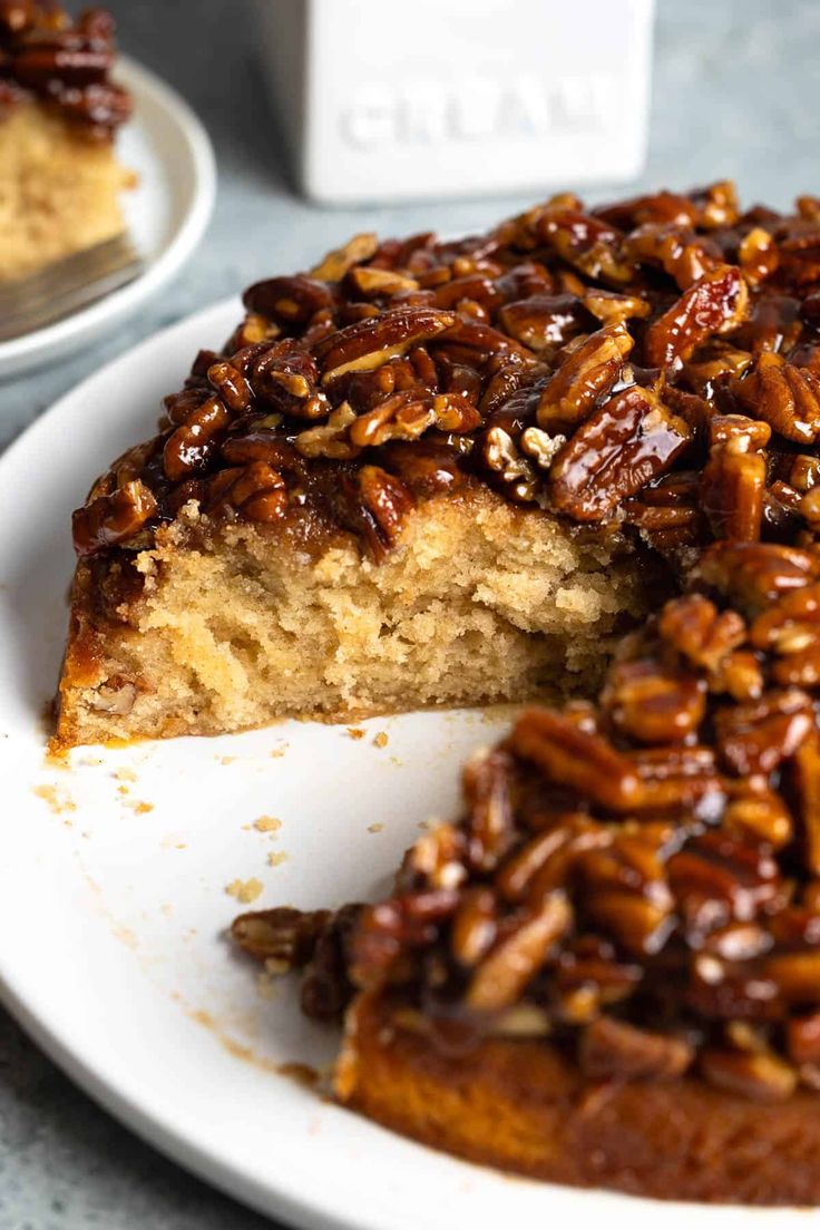 a pecan pie on a white plate with one slice cut out and ready to be eaten