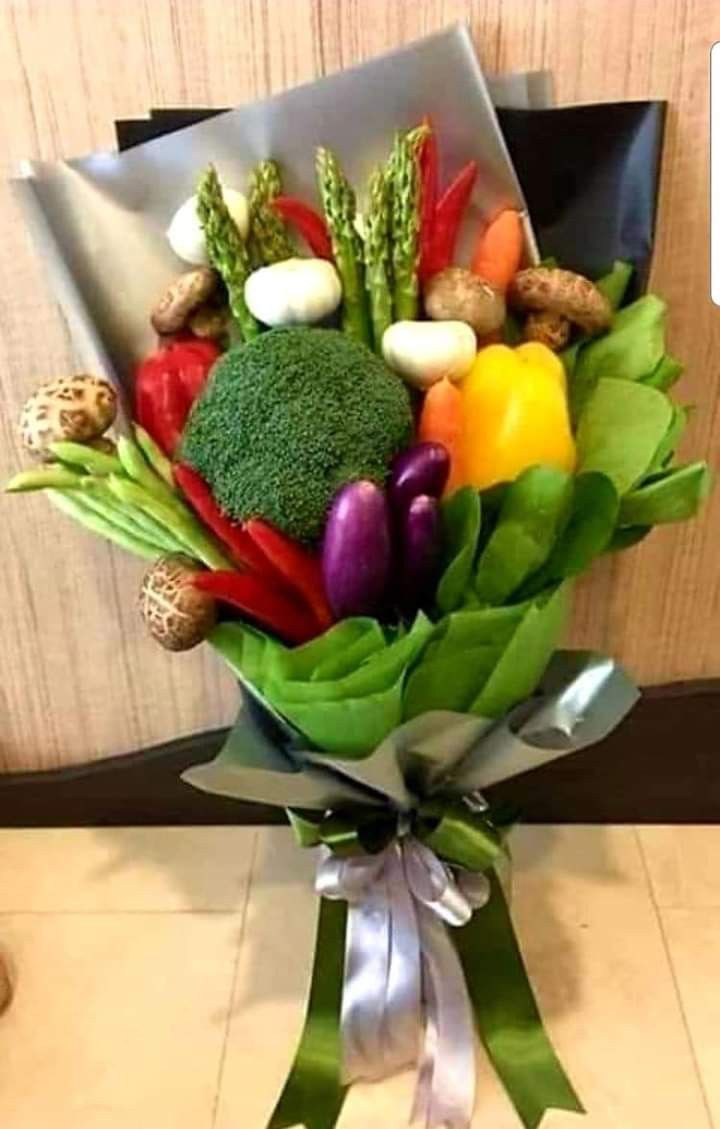 a bouquet of fresh vegetables is wrapped in green and white paper with a ribbon around it