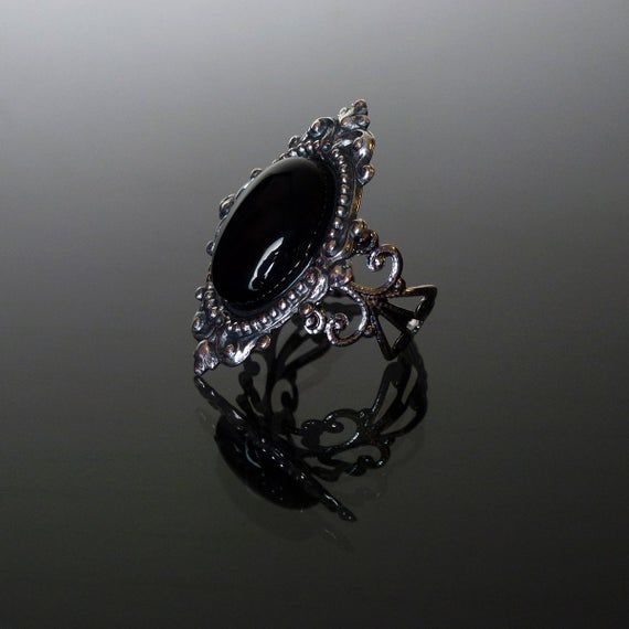 This ornate ring features a natural gemstone Black Onyx cabochon set in a beautifully decorative mount (measuring 35 x 25 mm) on a stunning filigree band. The Sterling silver plated filigree ring is adjustable so one size fits all. Nickel and lead free. This Sinistra Black Onyx filigree ring compliments perfectly our Sinistra lace choker which can be found in our Etsy store. The full Sinistra range of venise lace chokers and matching rings are available in Black Onyx, Black cameo, Sapphire blue, Vintage Gothic Wedding Rings, Black Cameo, Ornate Ring, Steampunk Rings, Gothic Ring, Lace Choker, Jewelry Lockets, Gothic Rings, Dope Jewelry