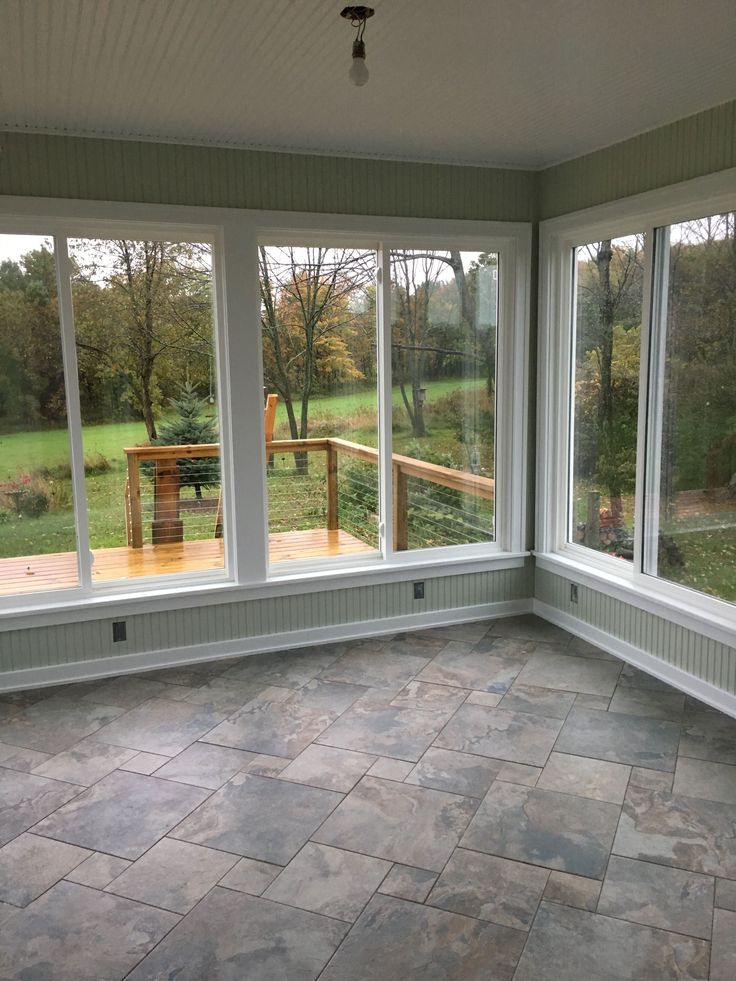 an empty room with large windows and stone flooring