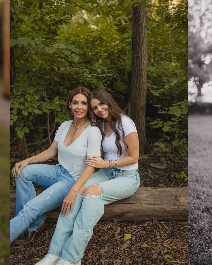 two women are sitting on a bench in the woods and one is holding her arm around another woman's shoulder